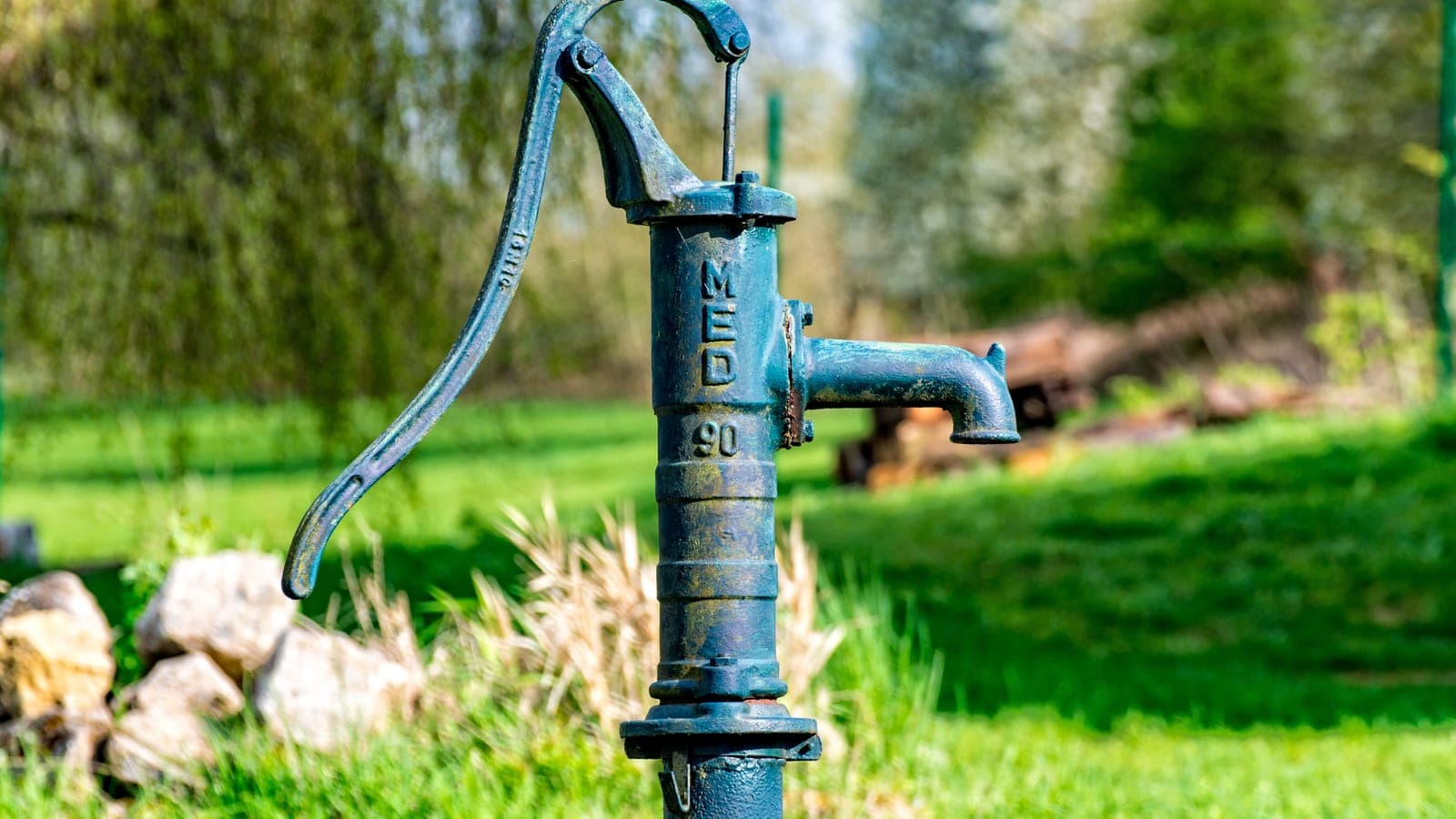 A maintained village water point with a worn but functioning hand pump.